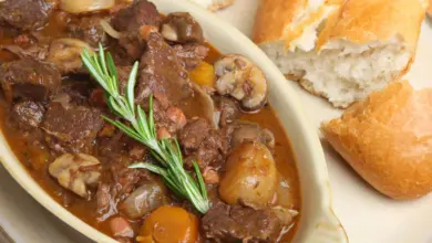 White Plate Filled with Beef Bourguignon Next to a Bread