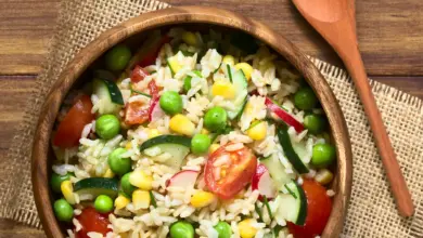 Brown Rice Salad on a Wooden Plate Next To a Fork