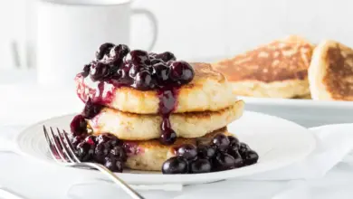 A Fluffy Blueberry Pancakes with Blueberry Sauce On A White Plate