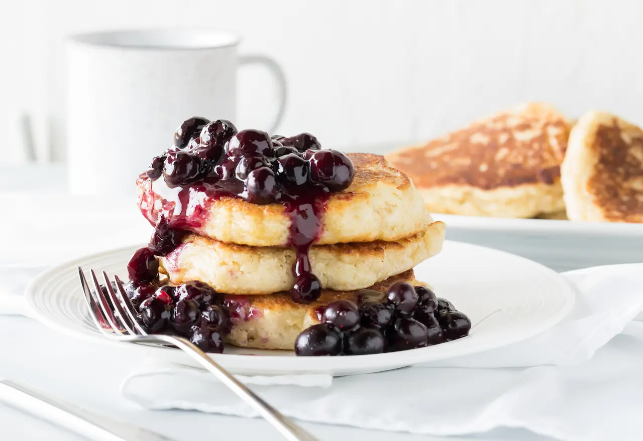 A Fluffy Blueberry Pancakes with Blueberry Sauce On A White Plate