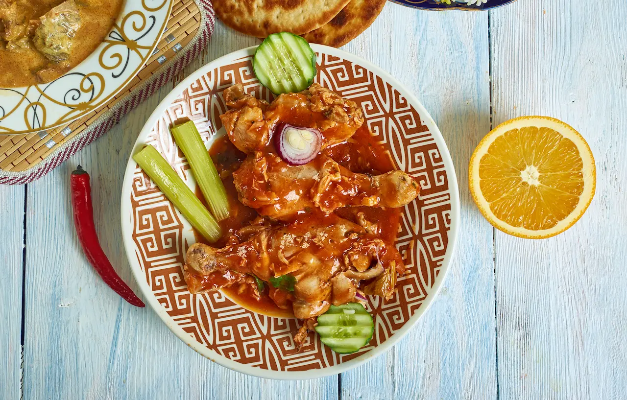 Kashmiri Chicken on a White Table Next to Orange