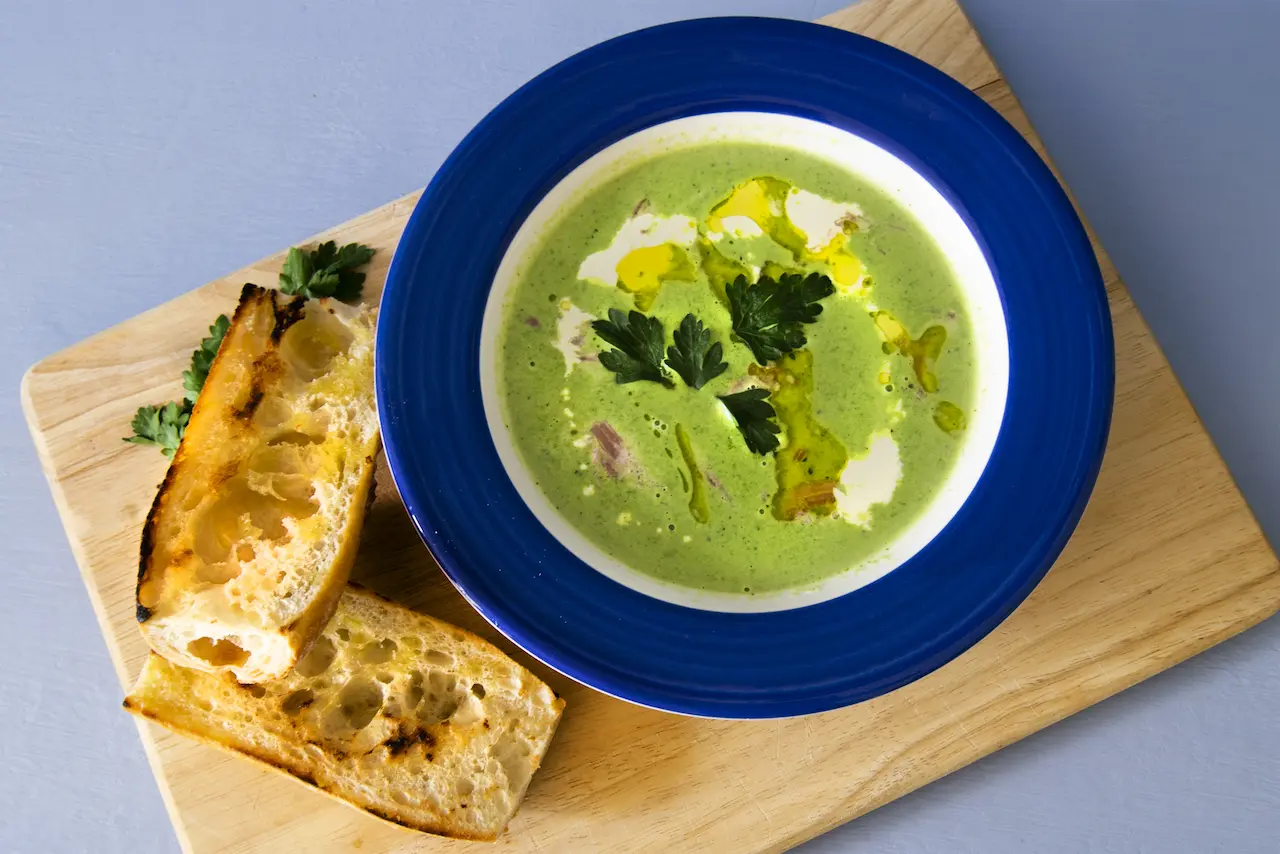 Pea and Ham Soup with Cream & Baguette on Rustic Board